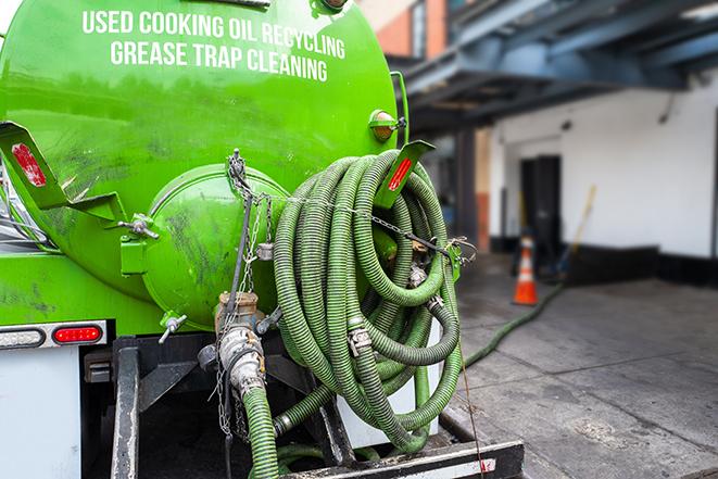 a technician pumping a grease trap in a commercial building in Garden City